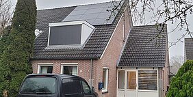 huis met zonnepanelen op het dak en een auto voor de deur