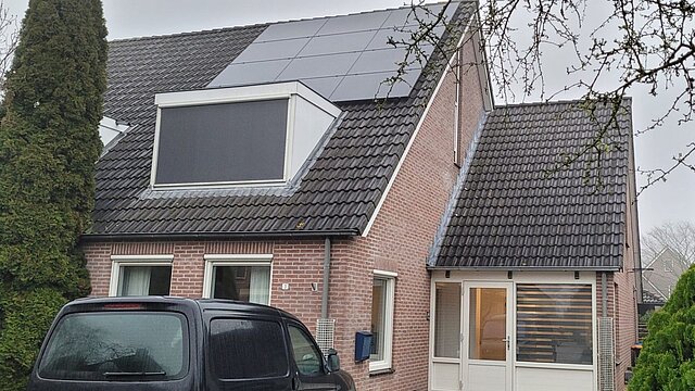 huis met zonnepanelen op het dak en een auto voor de deur