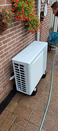 buiten unit van warmtepomp staat tegen buitenmuur aan