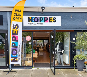 voorgevel van weggeefwinkel noppes, met vlag naast de deur