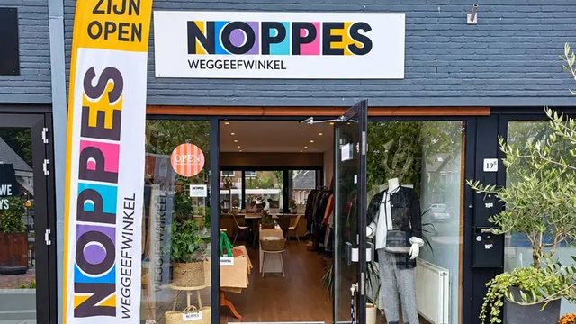 voorgevel van weggeefwinkel noppes, met vlag naast de deur