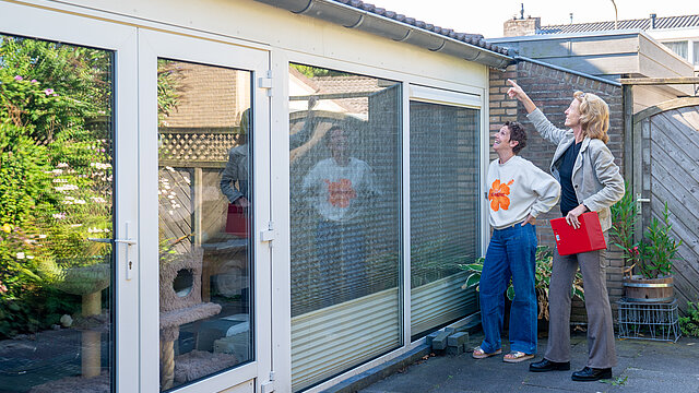 energieadviseur staat met mevrouw buiten en kijken naar het dak