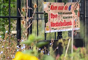 banner van open voedselbossendag tegen een glazen ruit aan