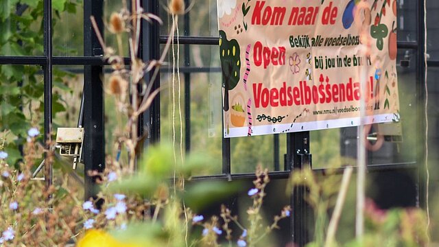 banner van open voedselbossendag tegen een glazen ruit aan